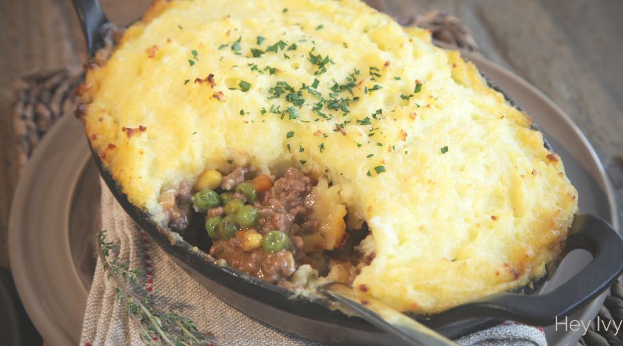 Warm cast iron dish with savory cottage pie topped with golden fluffy mashed potatoes